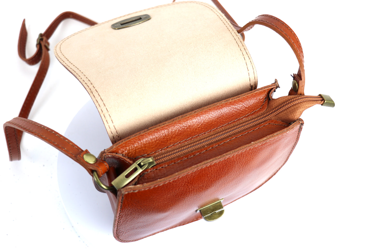 Open view of the light tan Cora Vintage Small Leather Crossbody Bag, showing a beige interior lining and space for essentials on a white background.
