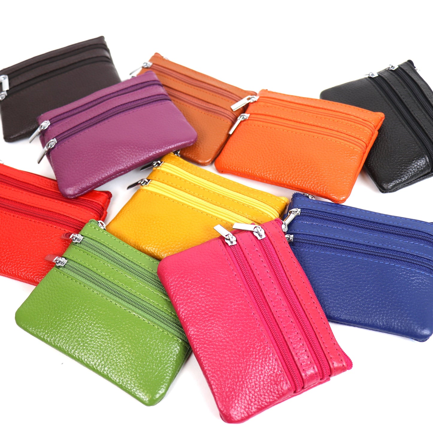 A collection of small leather pouches in various colors including Silver, Baby Blue, Denim Blue, Dusty Pink, Cherry, Yellow, Light Tan, Light Green, Cream, Dark Green, Beige, Royal Blue, Fuchsia Pink, Taupe, Purple, and Black, arranged in a scattered layout.