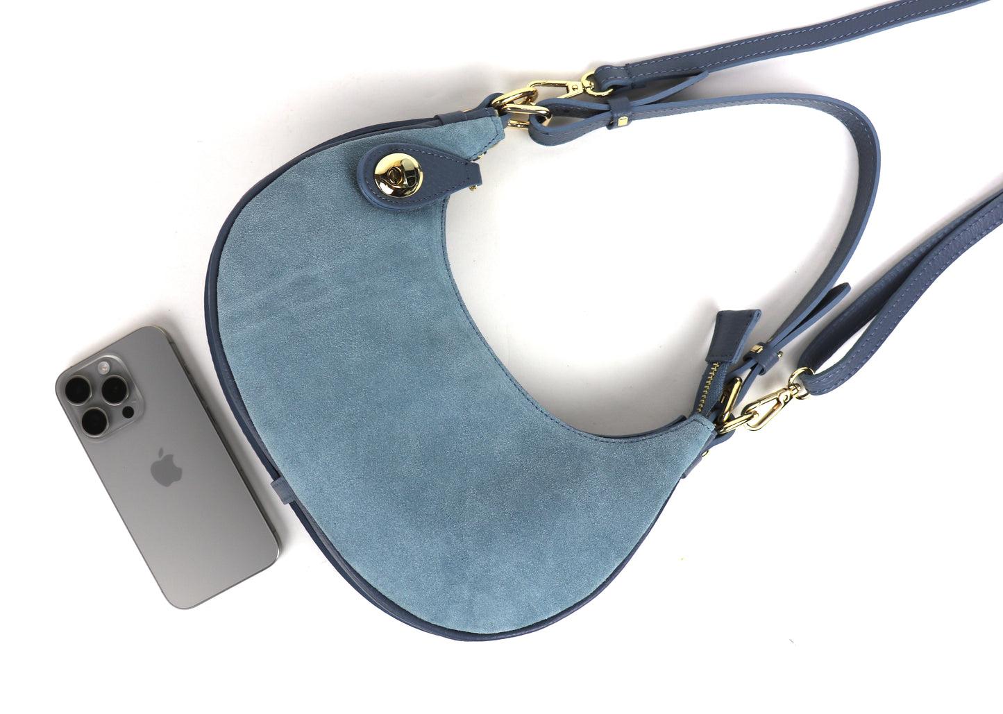 Denim Blue half moon bag laid flat with iPhone inside.