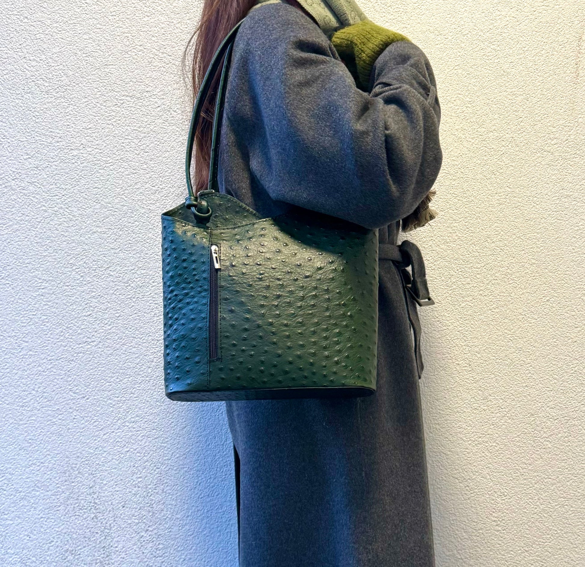 Woman wearing a Green Single-Tone Ostrich Style Italian Leather Convertible Handbag, back view showcasing the handbag worn as a crossbody.
