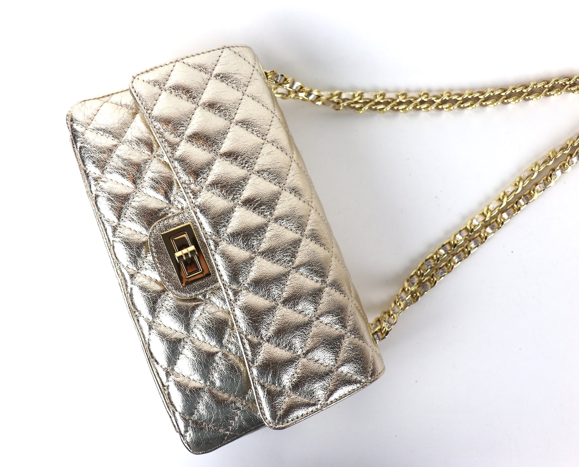 A gold quilted leather bag with a gold twist-lock closure and chain strap, displayed at an angle.






