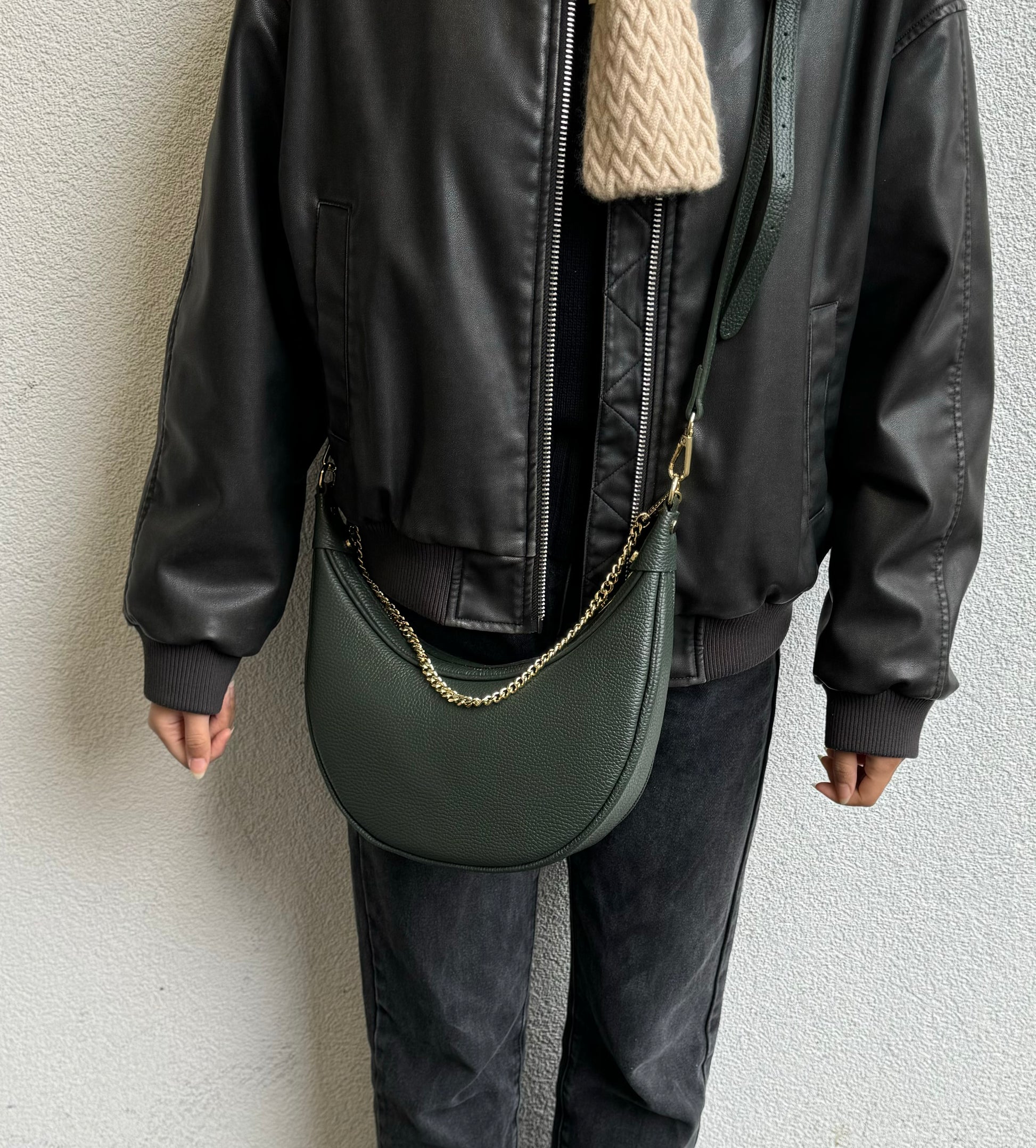 A person wearing the dark green crossbody bag with a gold chain, showcasing how it hangs from the shoulder.