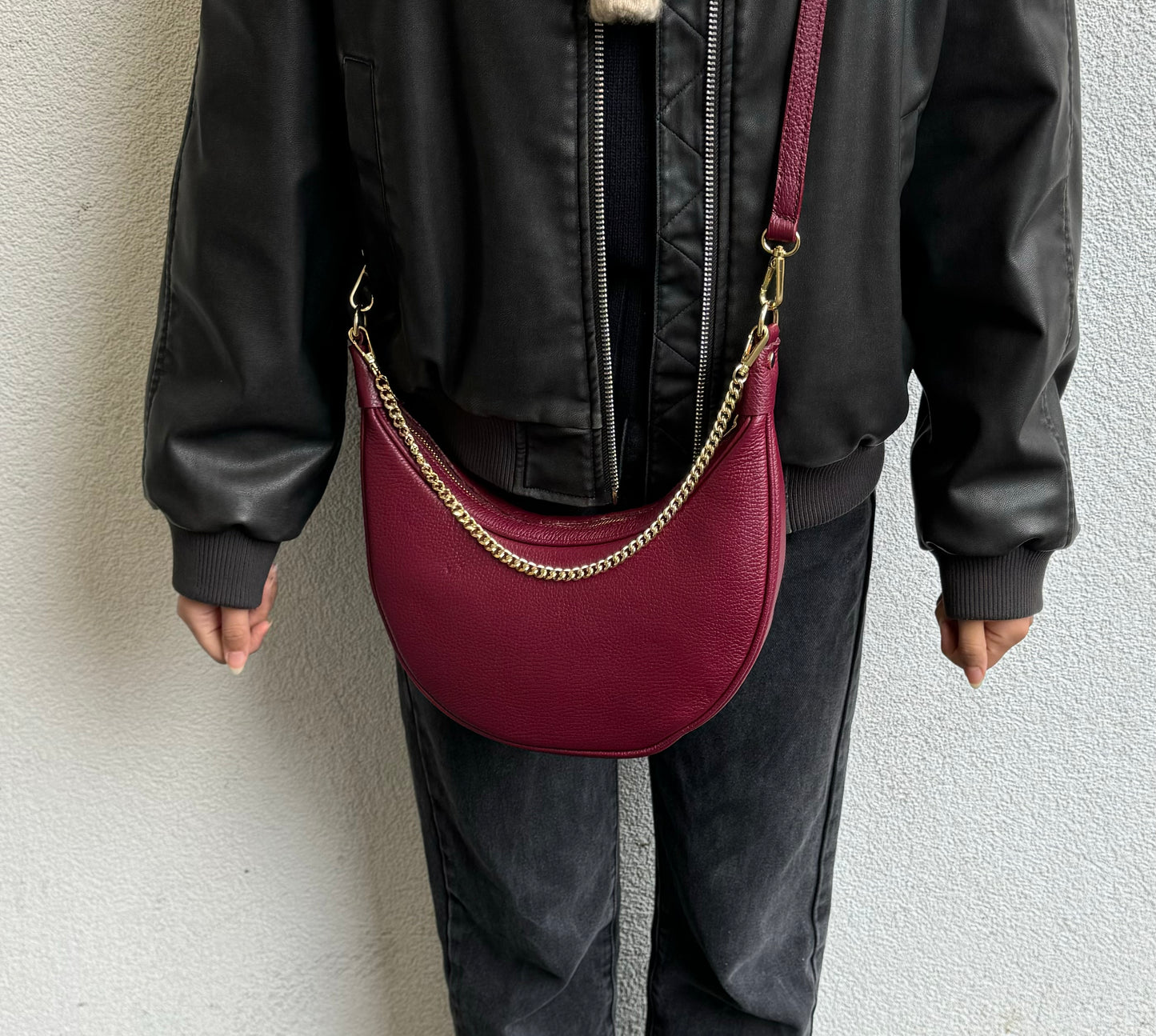 A burgundy leather crossbody bag with gold chain detailing, shown from the front against a white background.