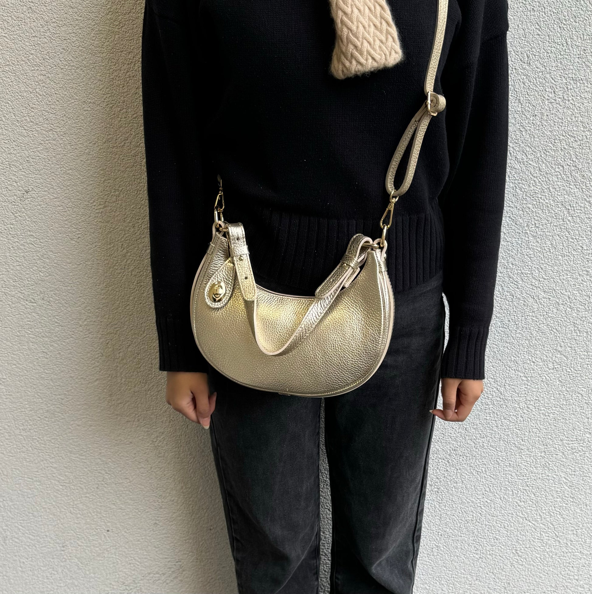 Person wearing Gold half moon bag as a crossbody.
