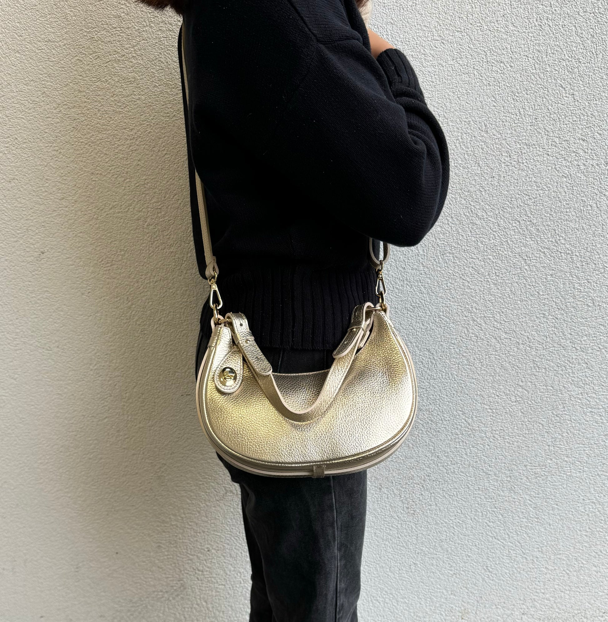 Person wearing Gold half moon bag as a crossbody.
