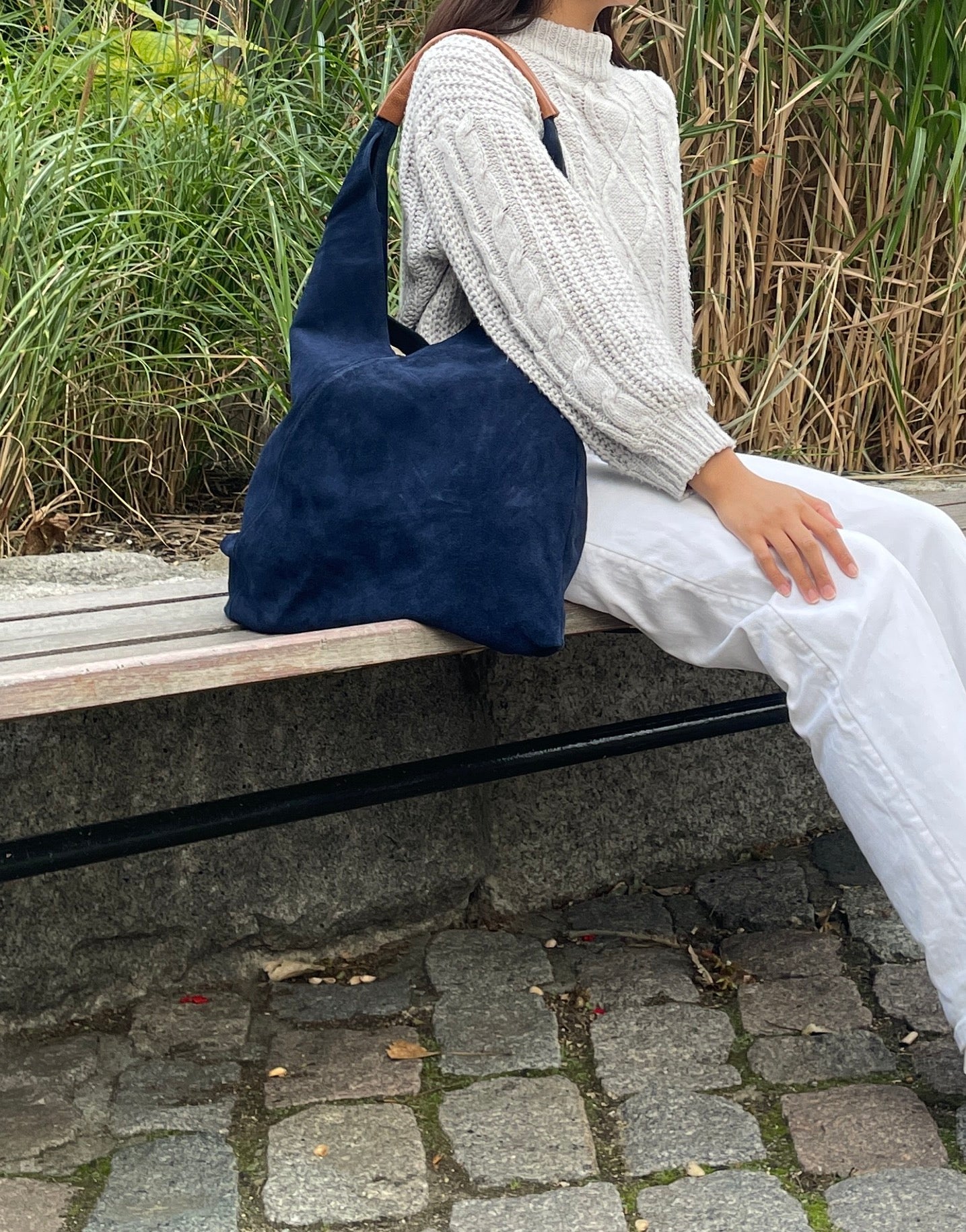 Model sitting on a bench with the Denim Blue Samantha Tote.