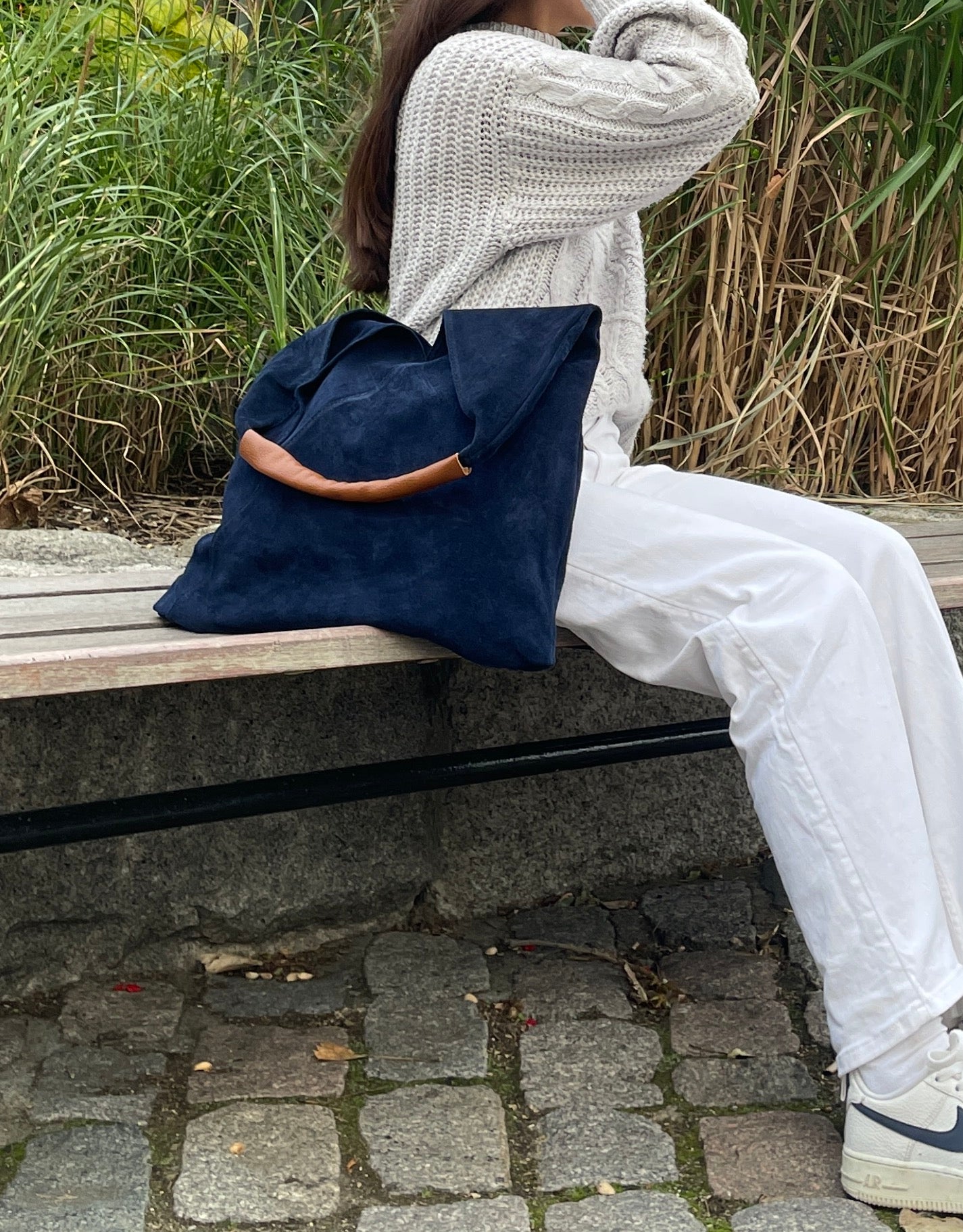 Model sitting on a bench with the Denim Blue Samantha Tote.