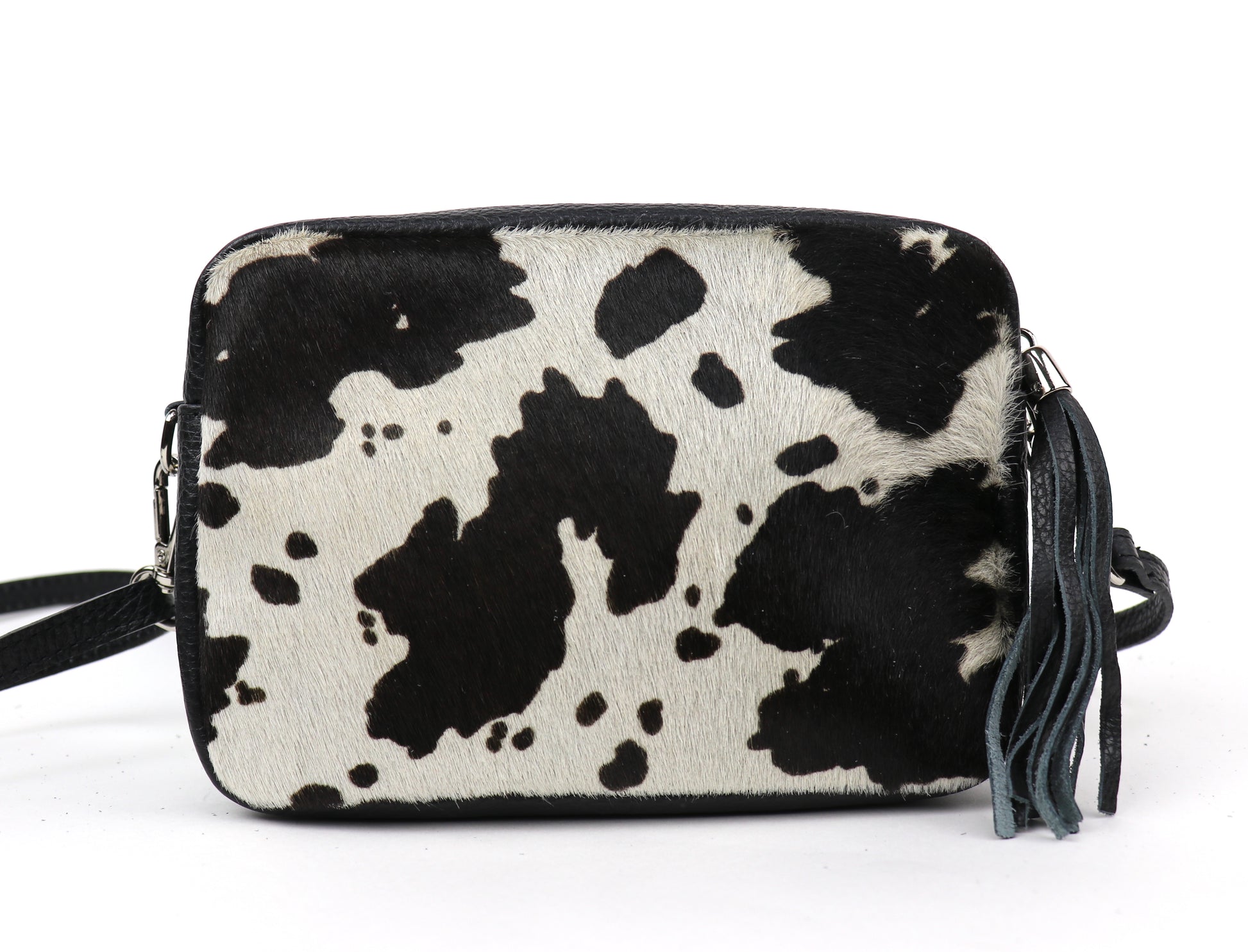 Cow print leather bag with detachable black strap and tassel, displayed front-facing.