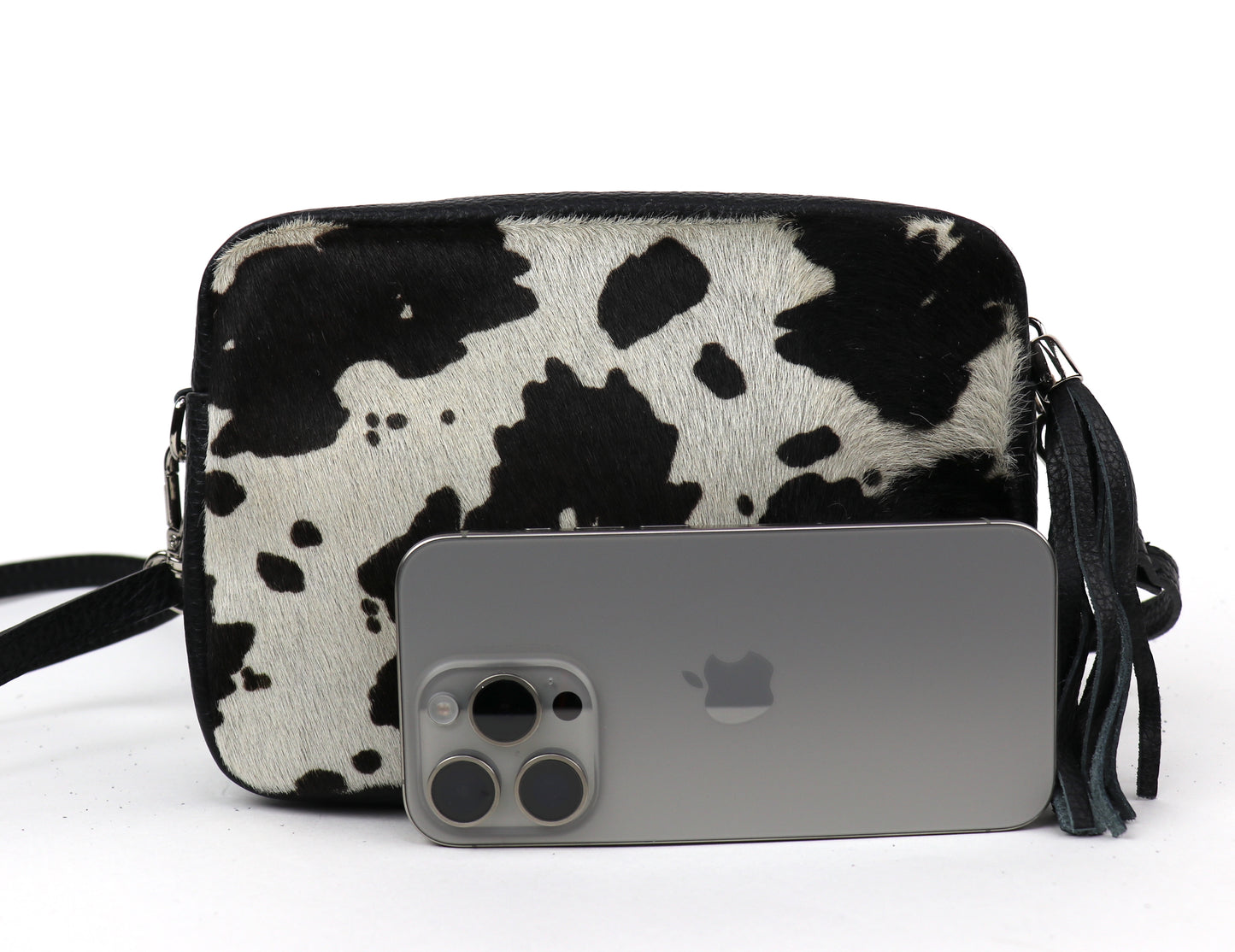 Cow print leather bag next to a smartphone, showing the bag's size relative to the phone.