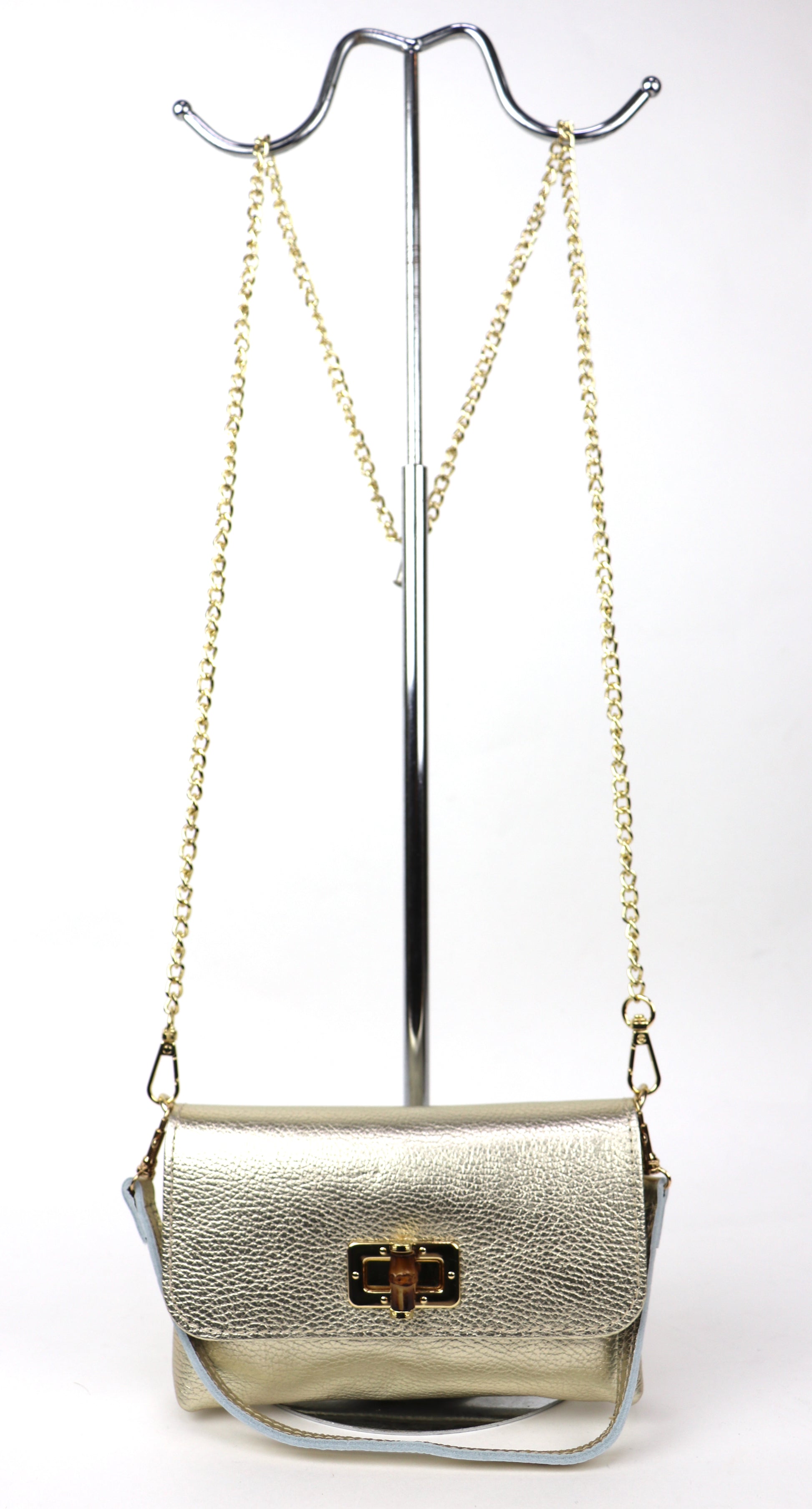 Gold metallic leather bag hanging from a gold chain, showing its overall shape.