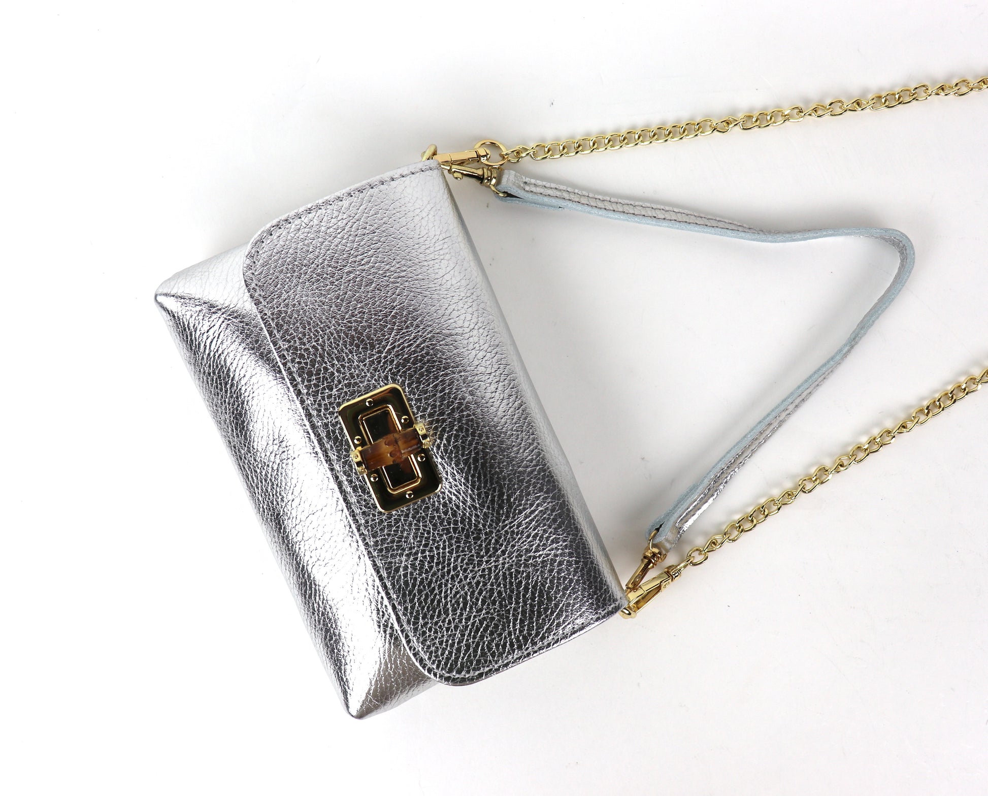 Angled view of a silver metallic leather bag, showcasing its shiny material and design.
