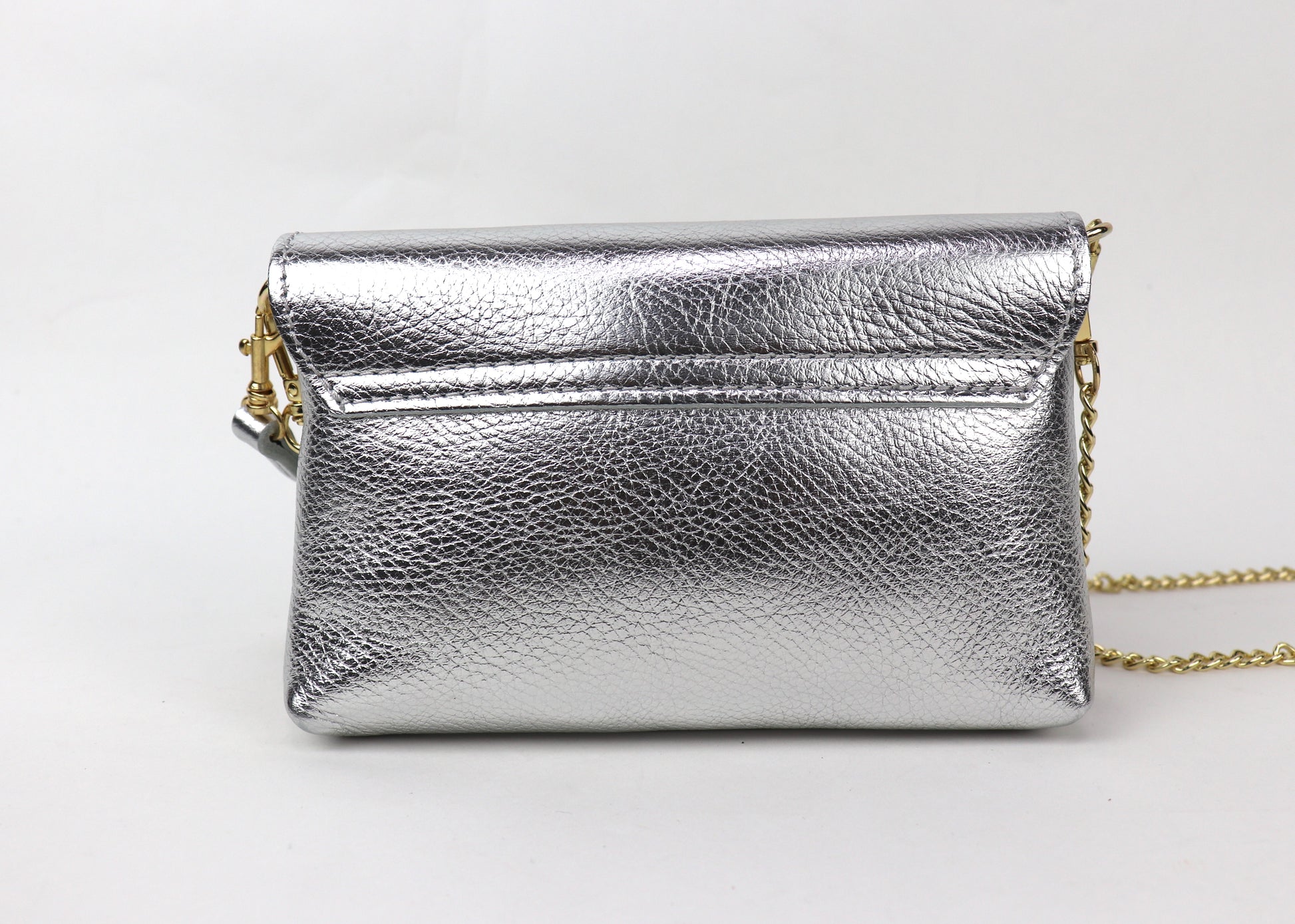 Back view of a silver metallic leather bag, showing the reflective surface and gold chain.