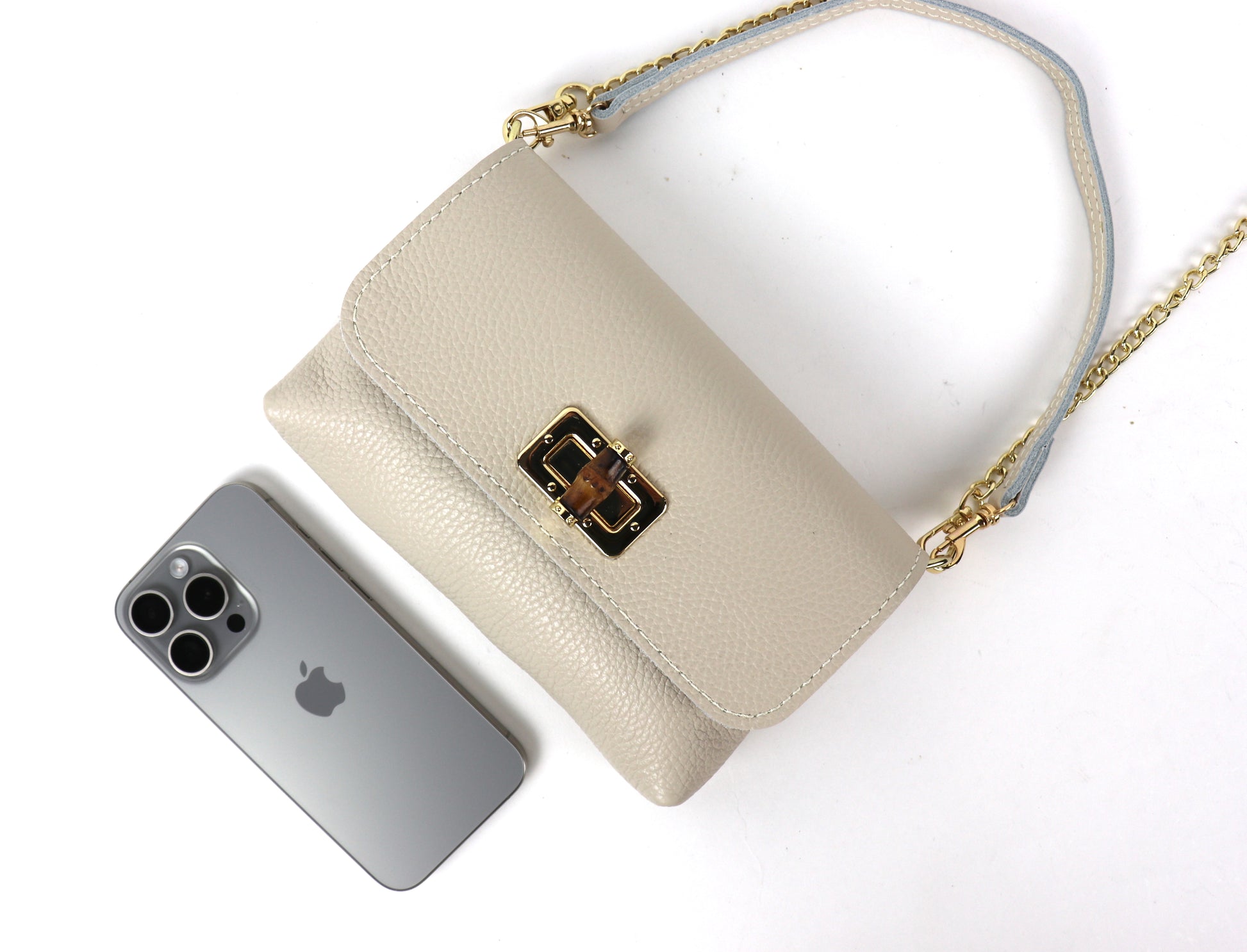 Cream leather bag next to a smartphone, illustrating the bag’s size.