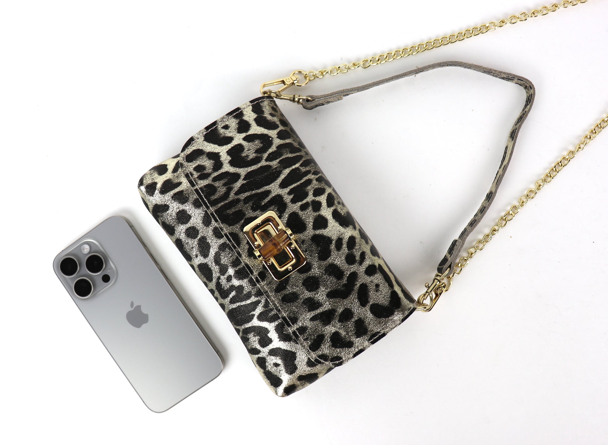 Gold leopard print leather bag next to a smartphone, demonstrating the bag’s size.