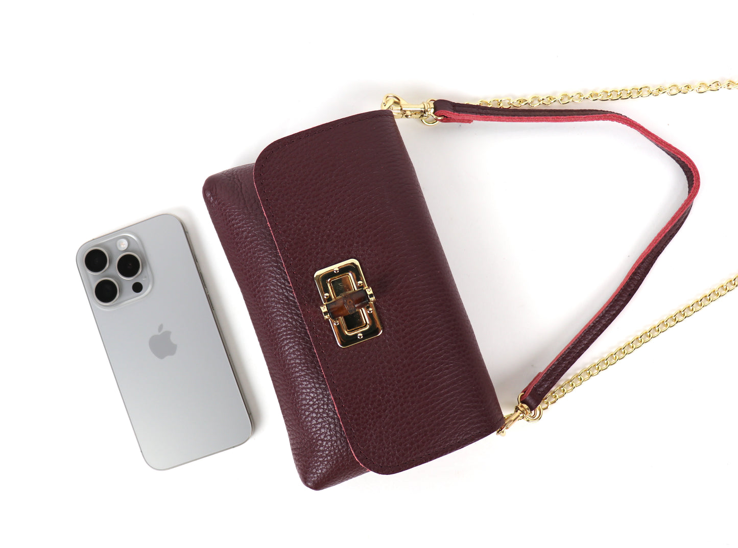 Burgundy leather bag displayed with a smartphone, emphasizing size.