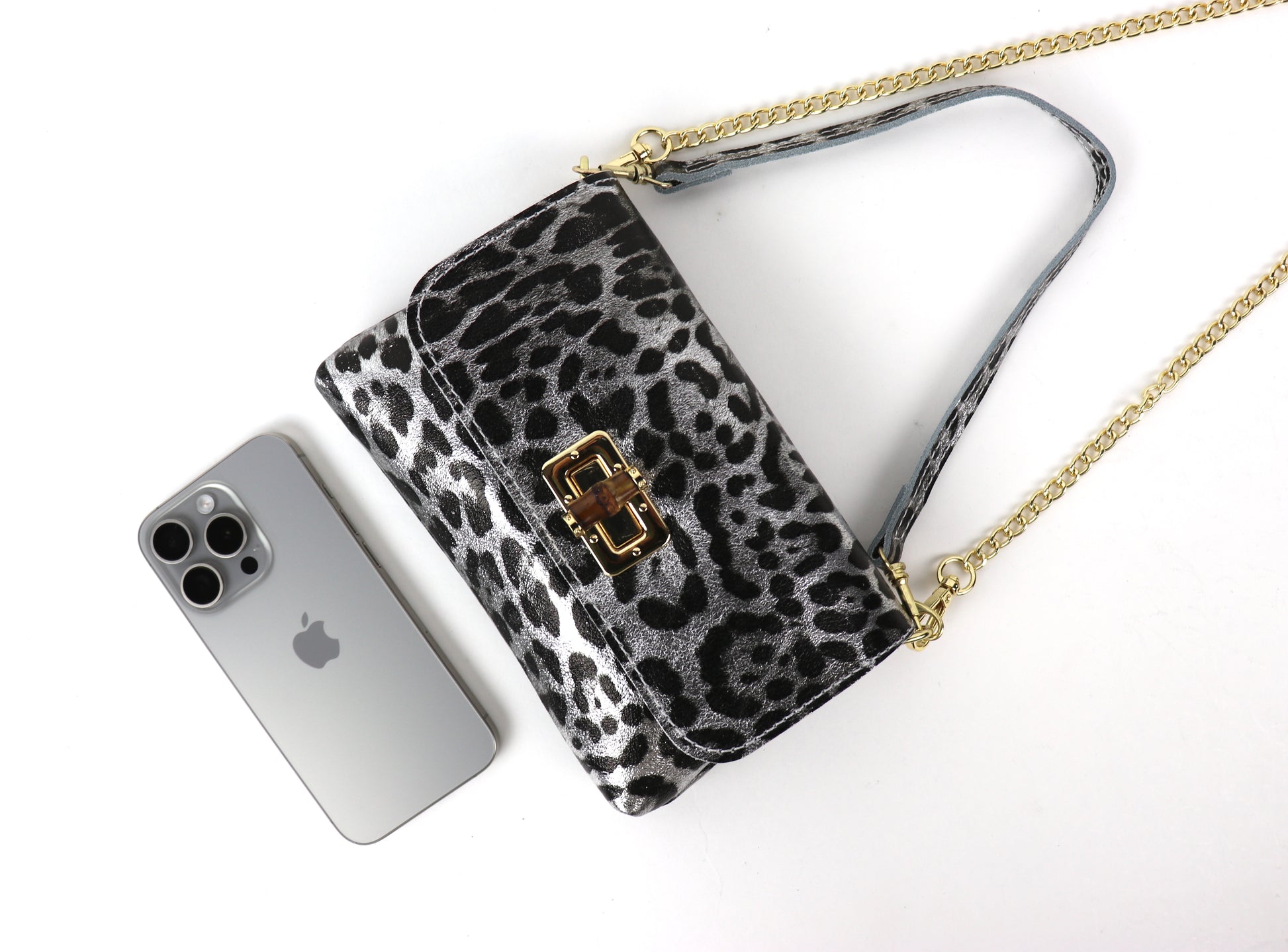 Silver leopard print leather bag next to a smartphone, demonstrating the bag’s size.