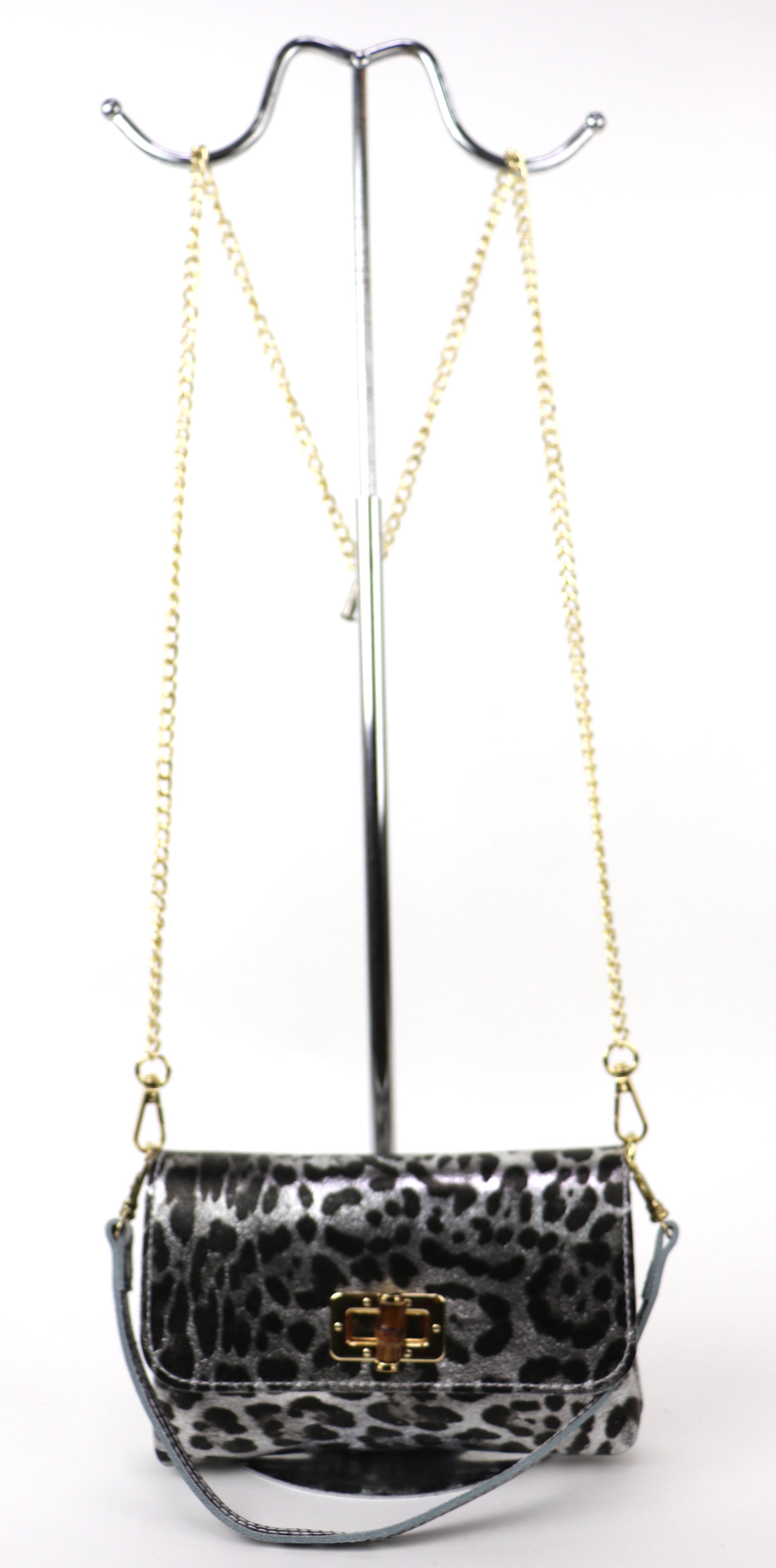 Silver leopard print leather bag hanging from a gold chain, showing the overall shape.