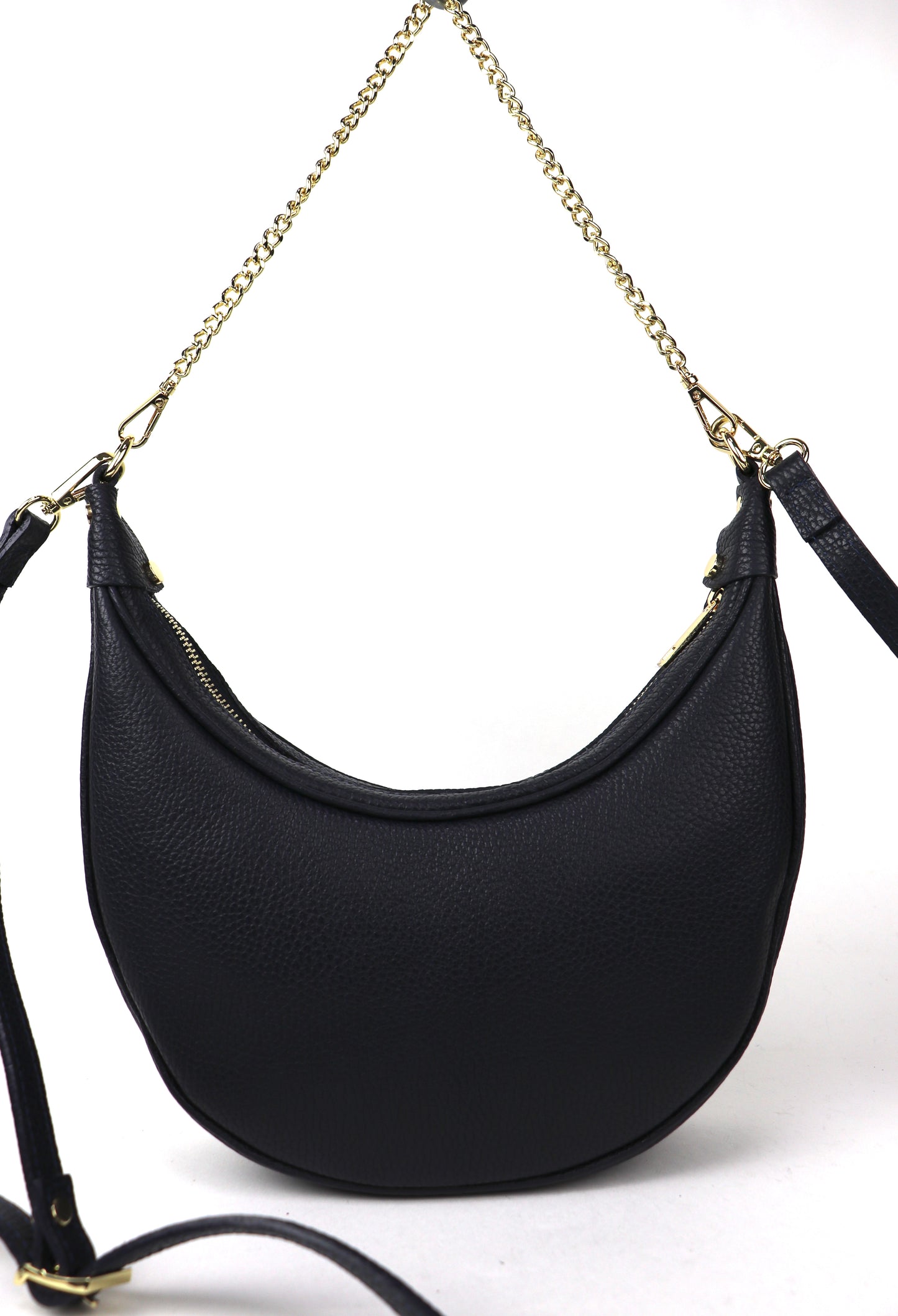 A navy crescent-shaped leather crossbody bag with a gold chain strap, photographed from the front against a white background. The bag is shown in a hanging position, highlighting its structured shape and luxurious gold detailing.