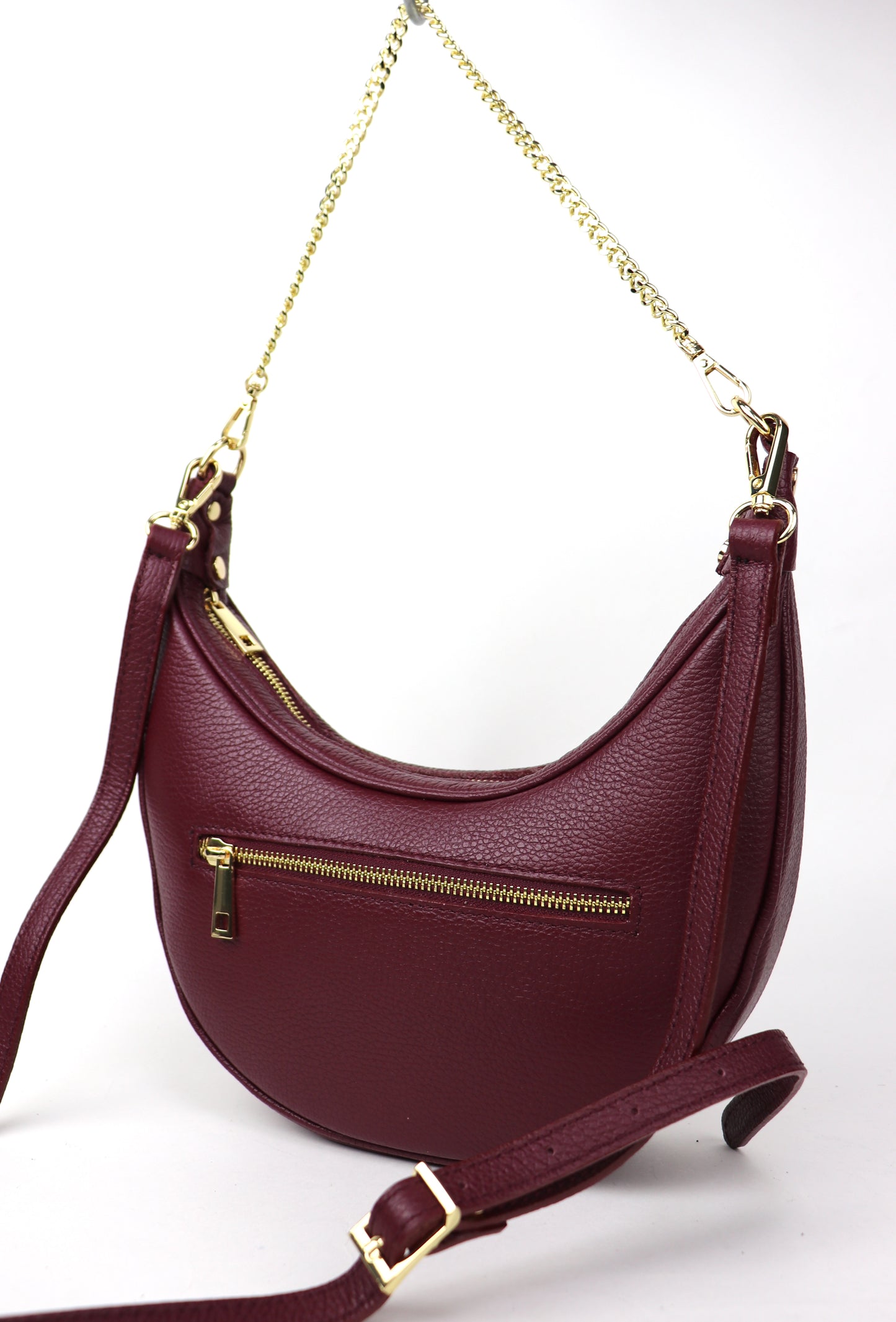 The back of the burgundy leather crossbody bag with a zipper pocket, shown on a white background.