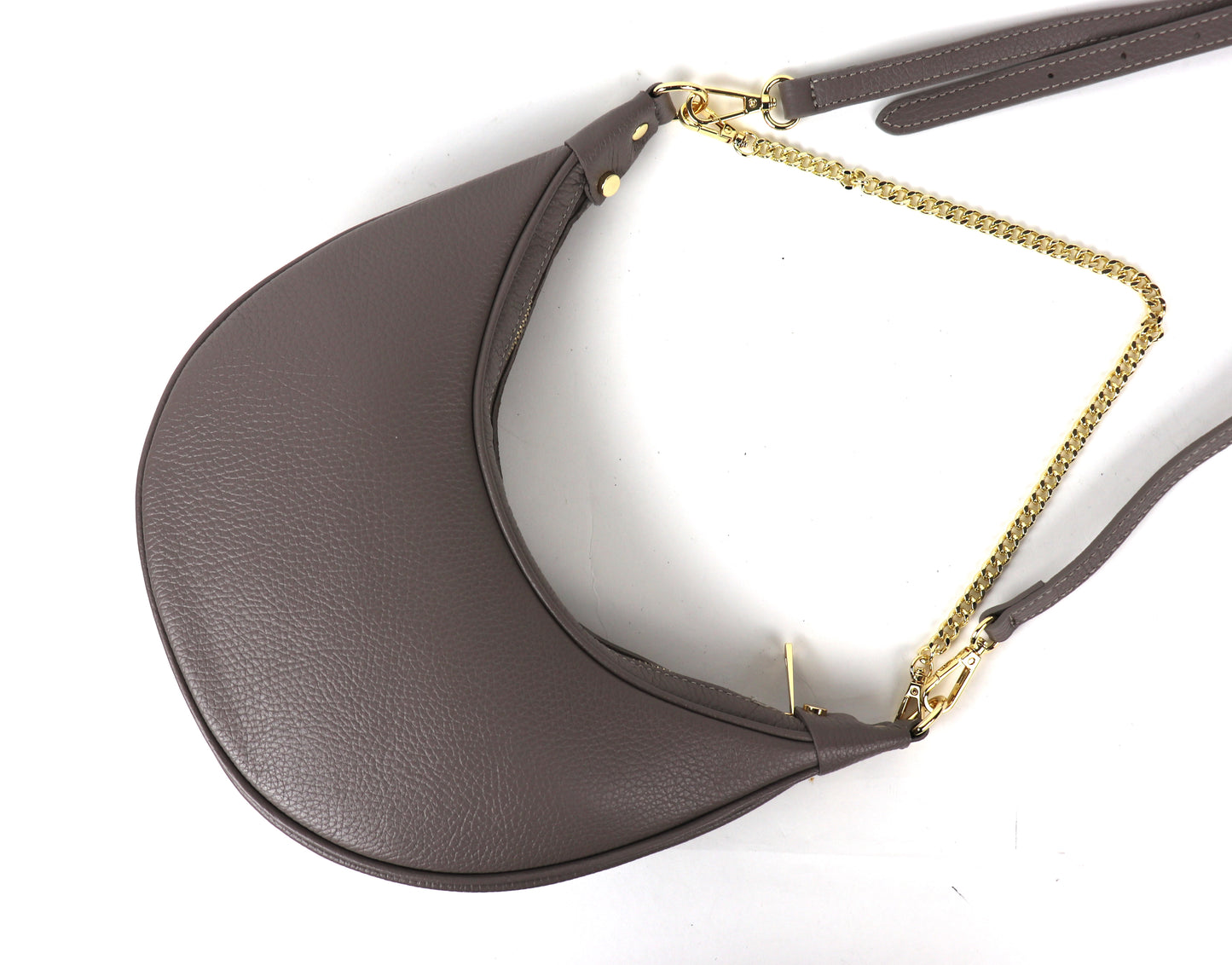 A taupe crescent-shaped leather crossbody bag with a gold chain strap, photographed from the top. The smooth texture of the leather is visible, and the adjustable strap is resting beside the bag.