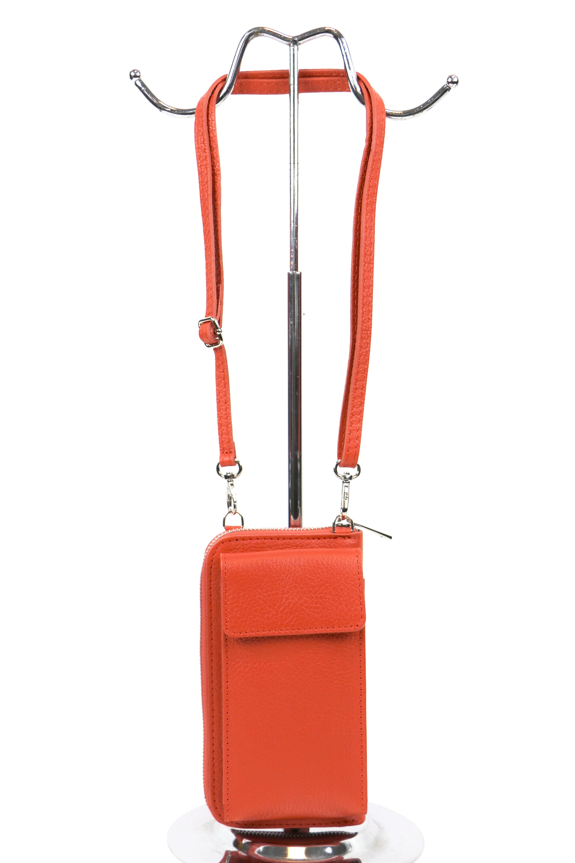 Orange crossbody bag with an adjustable strap hanging on a metal stand.