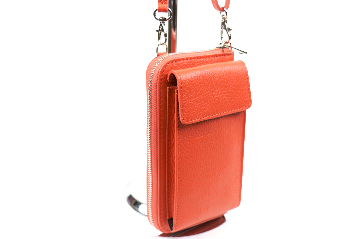 Orange crossbody bag with a front flap pocket and zipper detail, hanging on a metal stand.






