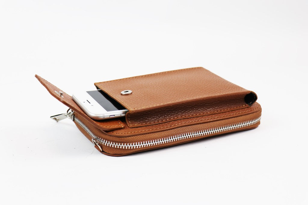 Brown crossbody bag with a phone partially inserted in the front flap pocket.