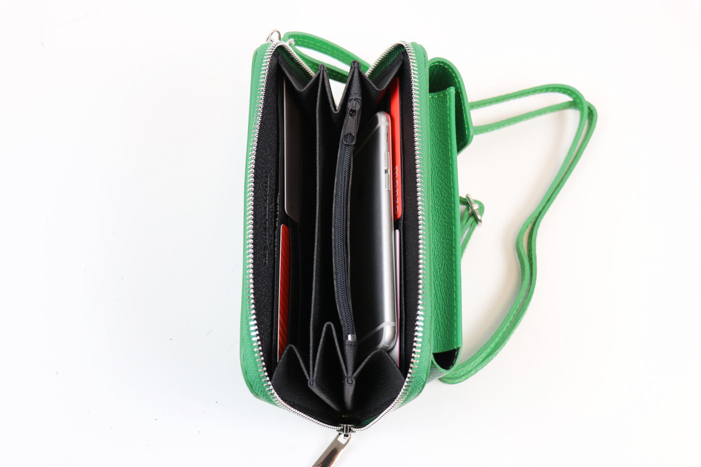 Open green crossbody bag displaying multiple compartments with a phone and cards stored inside, along with an attached green strap.






