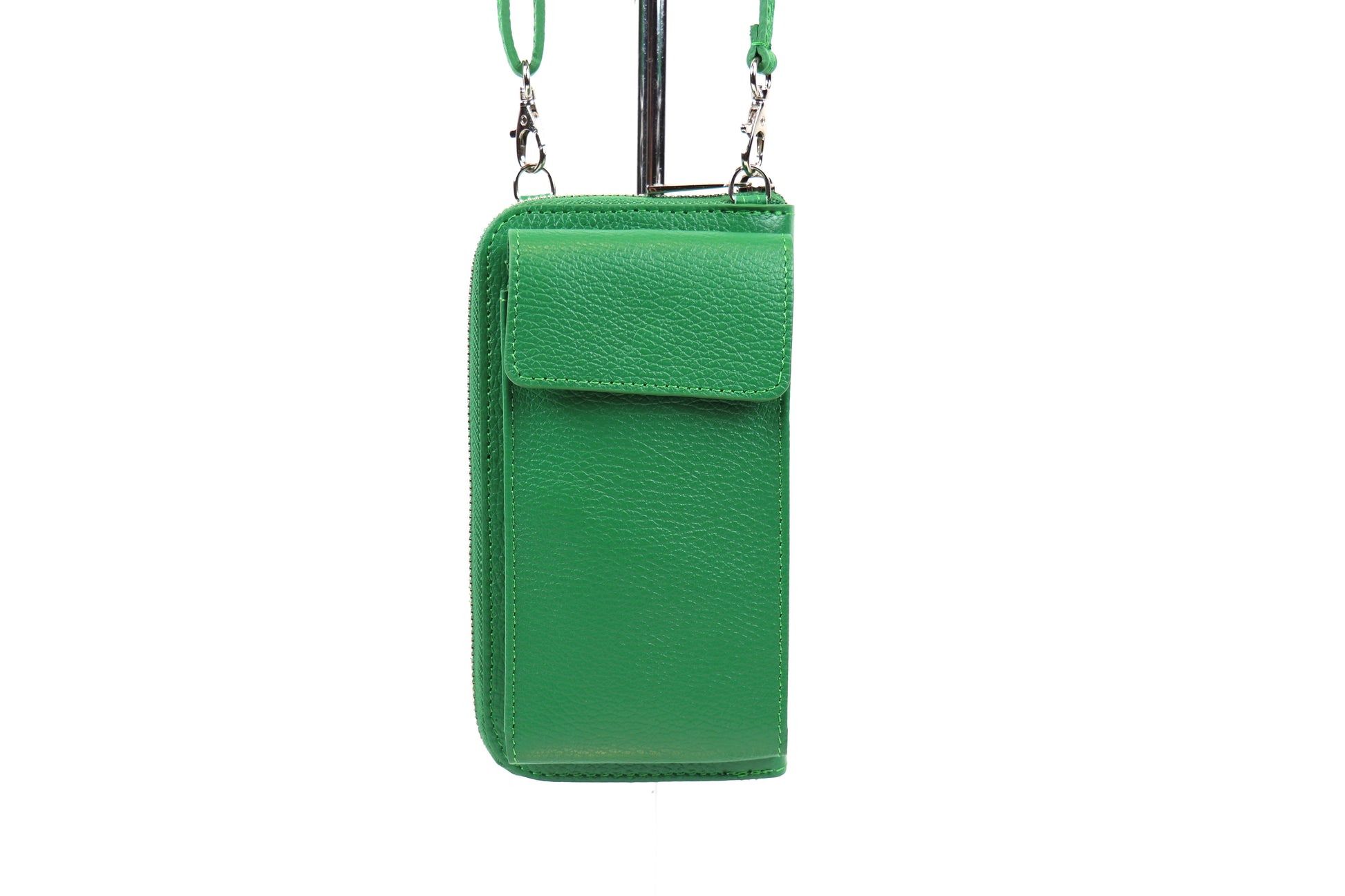 Green crossbody bag with a front flap pocket and adjustable strap, hanging on a metal stand.






