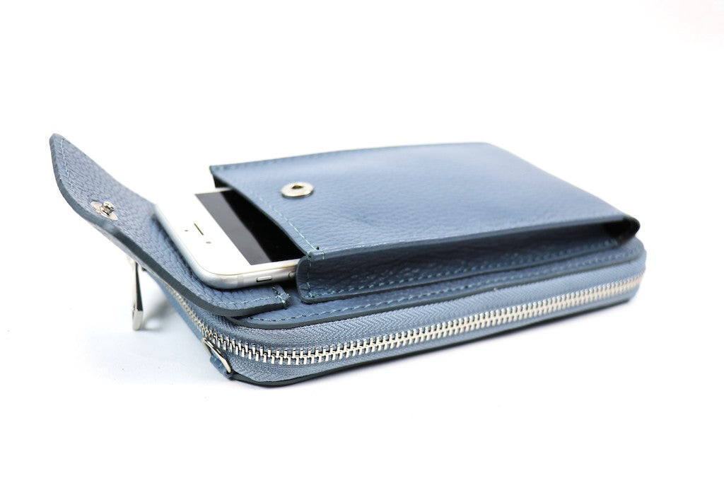 Blue crossbody bag with a phone partially inserted in the front flap pocket.