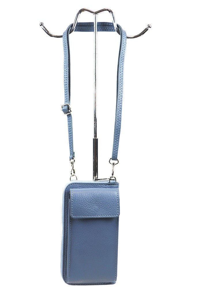 Blue leather crossbody bag with adjustable strap hanging on a metal stand.