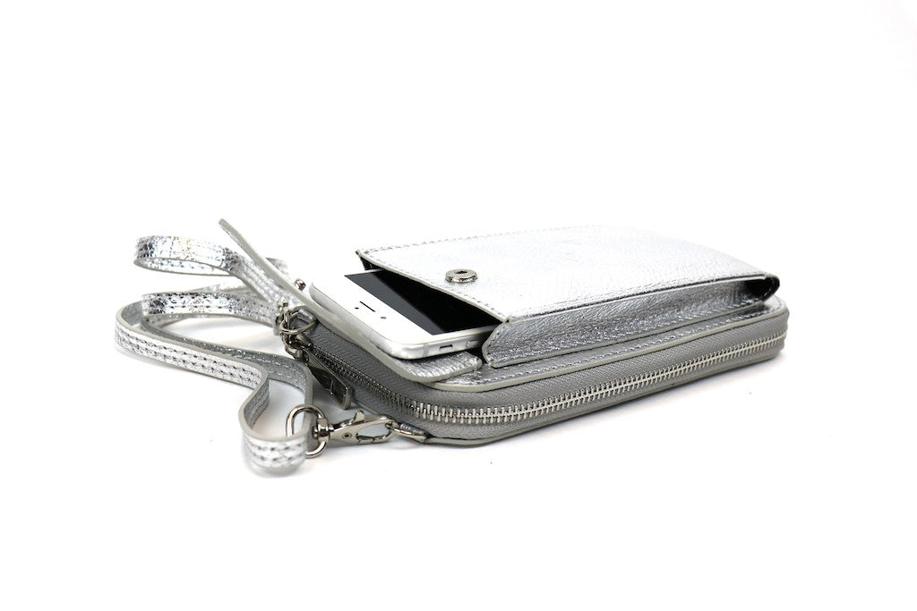 Silver metallic crossbody bag with a phone partially inserted in the front flap pocket.