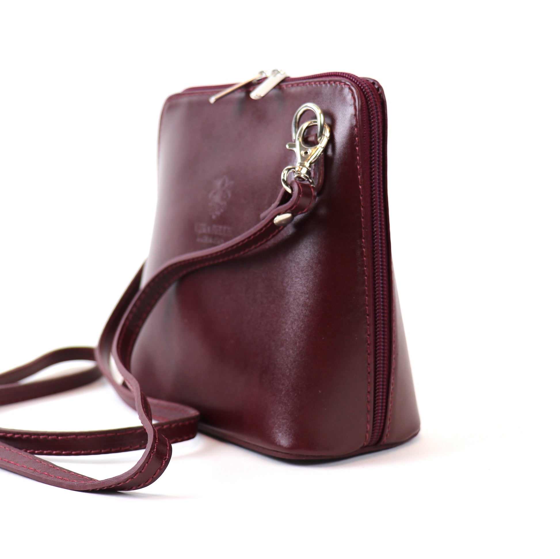 Side view of a Burgundy Small Handmade Leather Crossbody Bag featuring a smooth leather finish, detachable strap, and silver-tone hardware.

