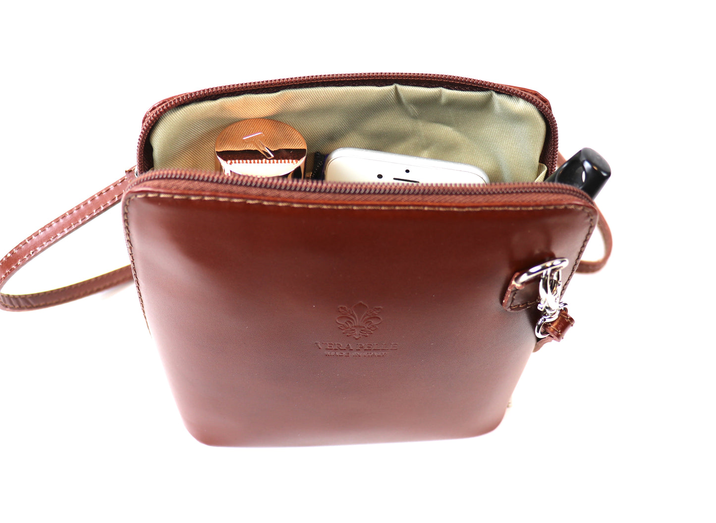 Top view of a tan Small Handmade Leather Crossbody Bag with an open zipper, showing interior contents including a phone, compact mirror, and lipstick.

