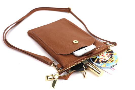 Tan Leather Travel Bag with a front pocket, displaying keys and small items spilling out, showcasing the bag's storage capacity.
