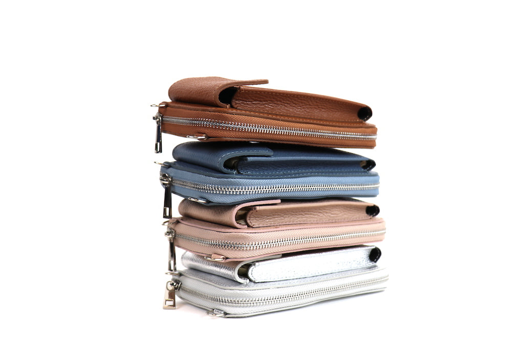 Stack of four leather wallets in brown, blue, beige, and silver, showing their zippers and textured material.