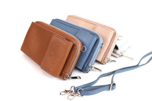 Three textured leather wallets in brown, blue, and beige with wrist straps and silver hardware.