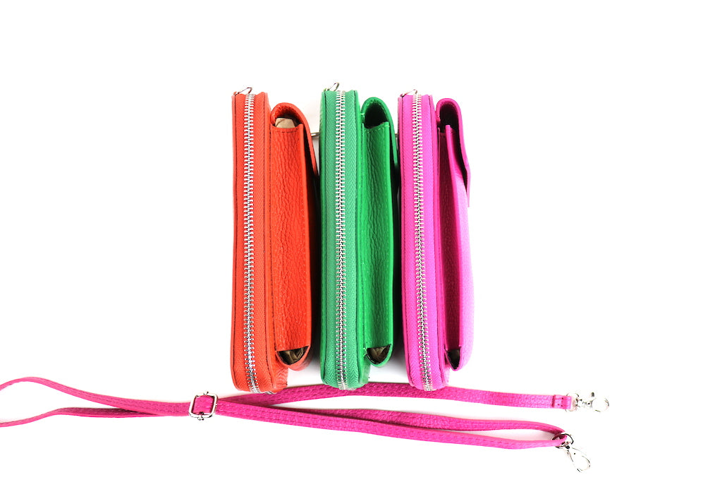 Side view of crossbody bags in orange, green, and pink lined up, with a pink detachable strap placed beside them.