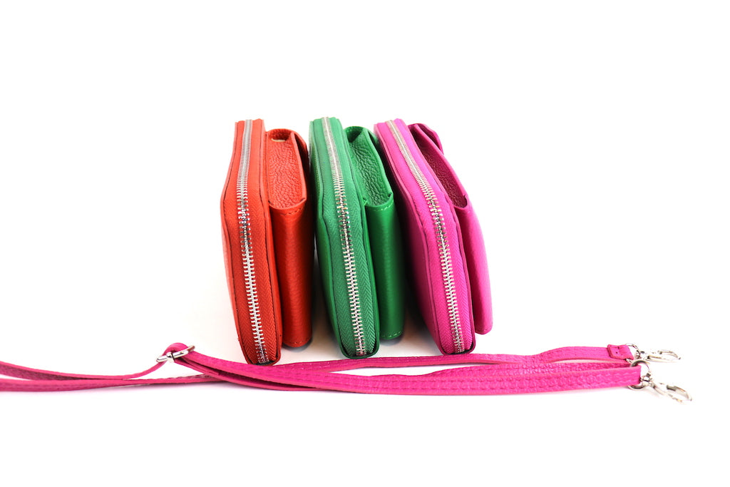 Side view of crossbody bags in orange, green, and pink lined up, with a pink detachable strap placed beside them.